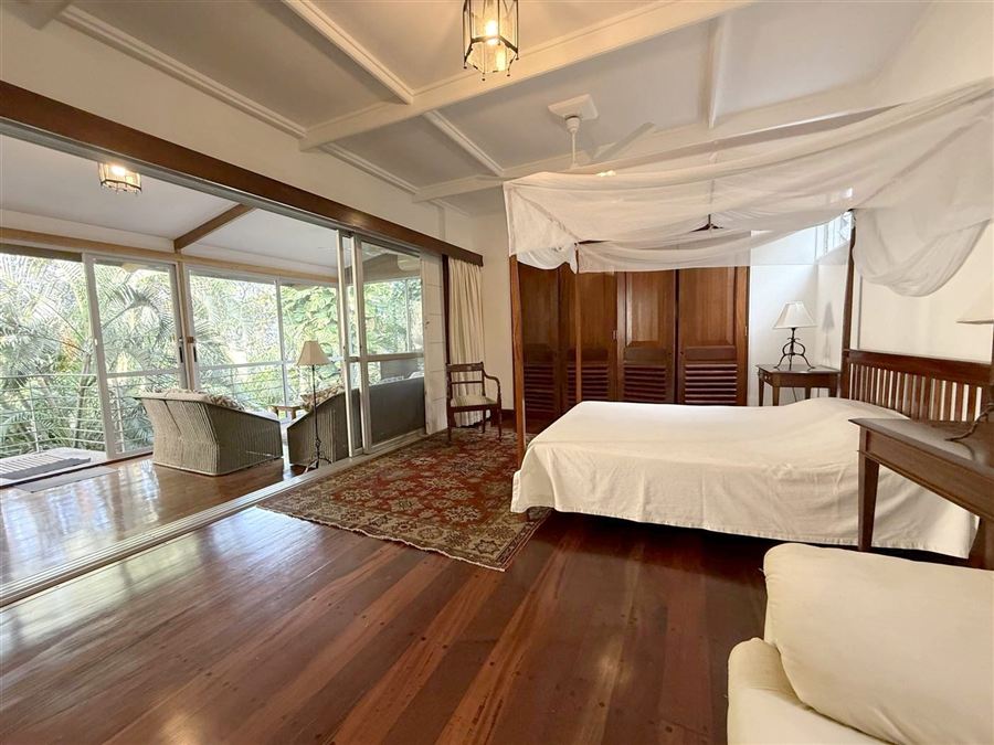 Bedroom with timber floor, opening onto a veranda
