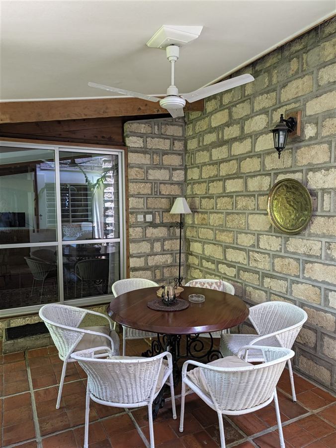 A veranda with a round table and white chairs