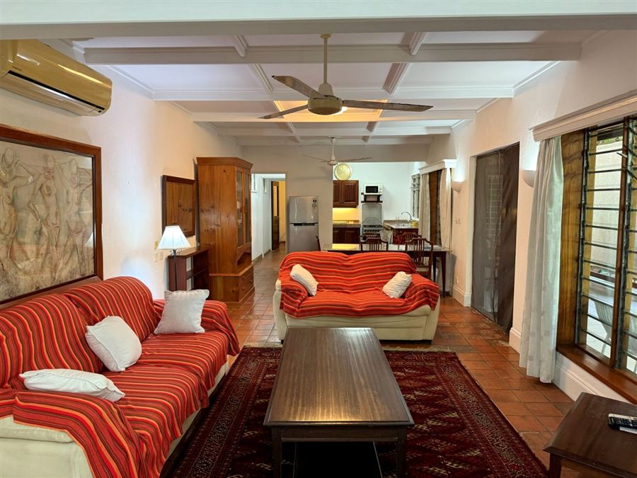Long living room with red sofas and a kitchen beyond