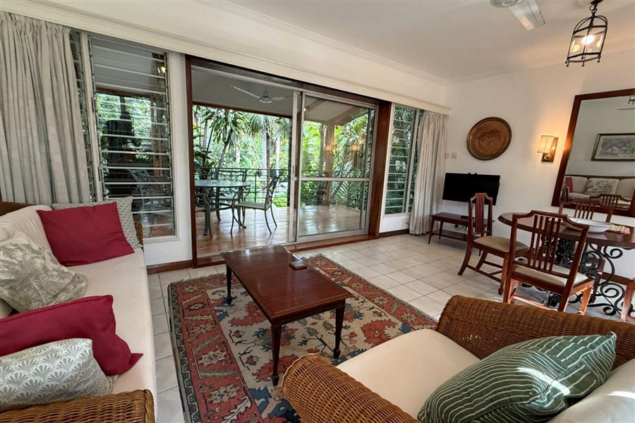 Living room with sliding doors open to a veranda in the trees