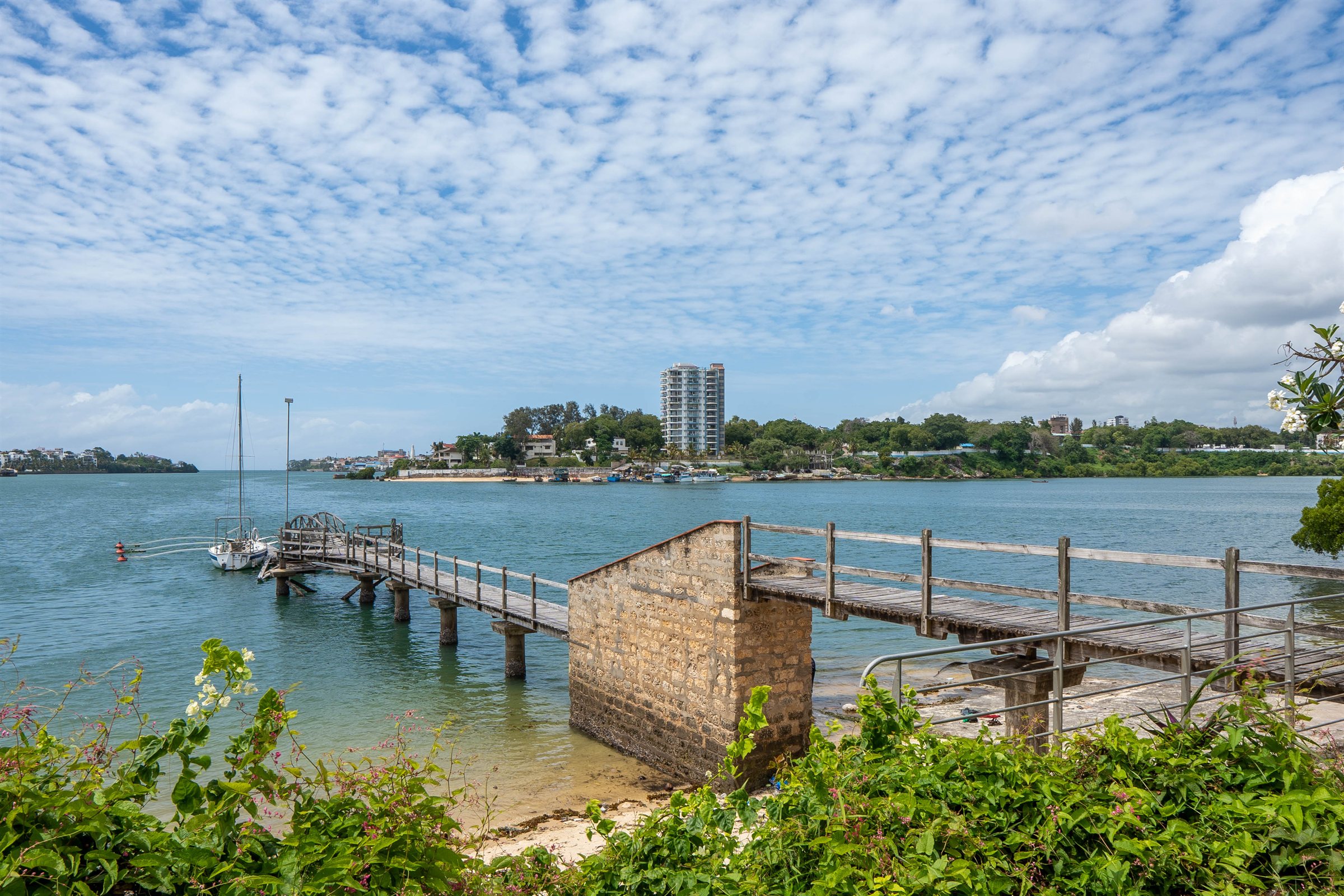 The wooden jetty running out into Tudor Creek, with a yacht moored at the end