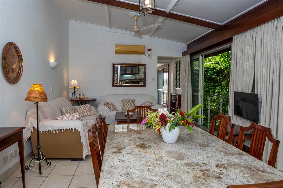 Living room with sofas and a dining table, opening onto the garden