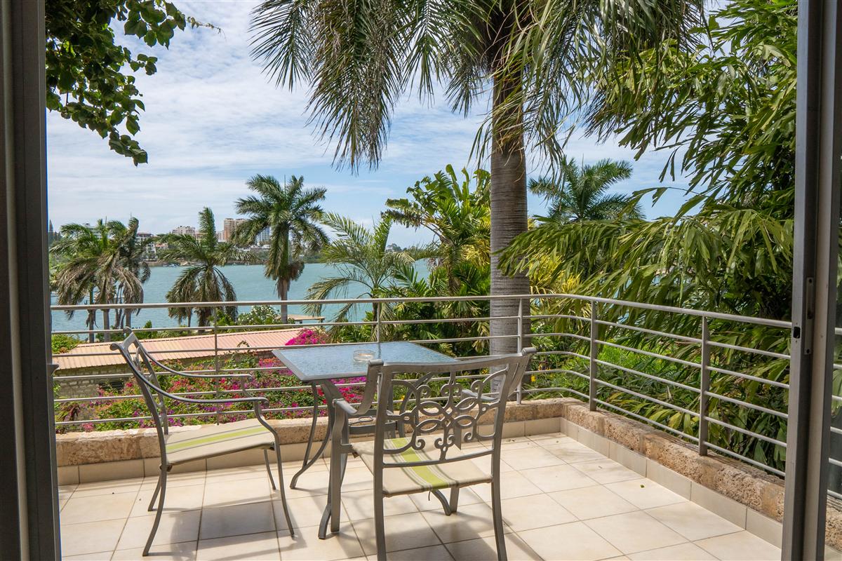 Looking out from the apartment to a private balcony, palms and the creek