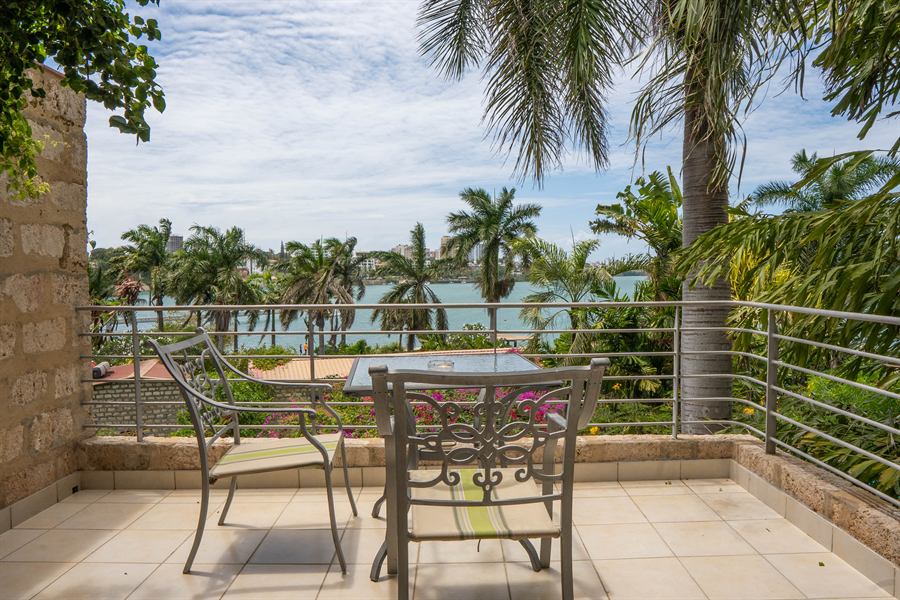 A balcony with a table and chairs, looking through palms to the creek