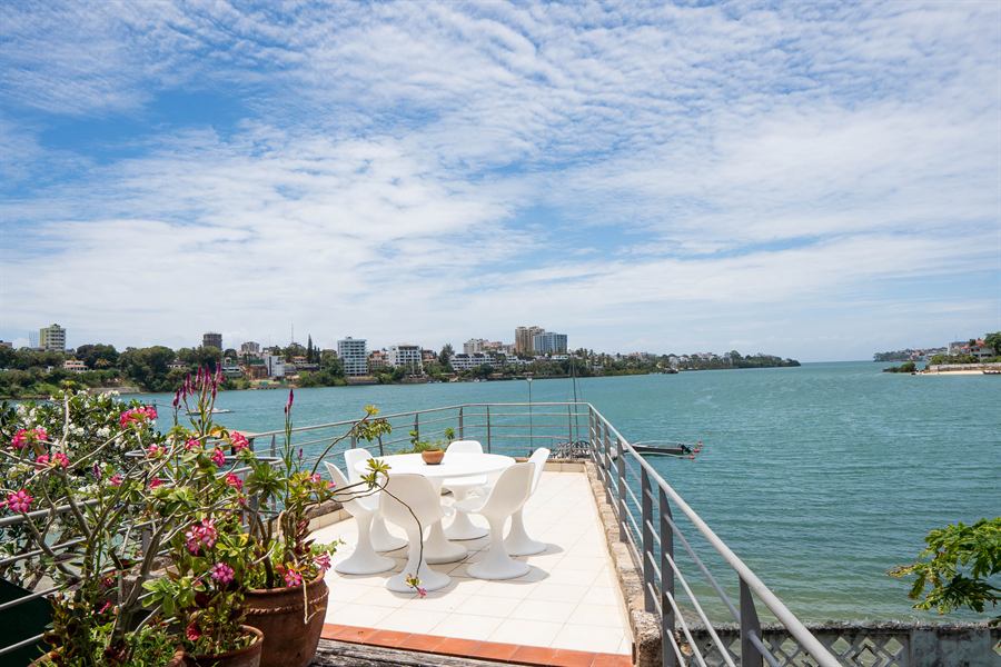 A white table and chairs on a deck right over the water